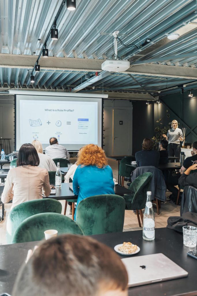 A business meeting with diverse attendees listening to a presentation in a modern conference room.