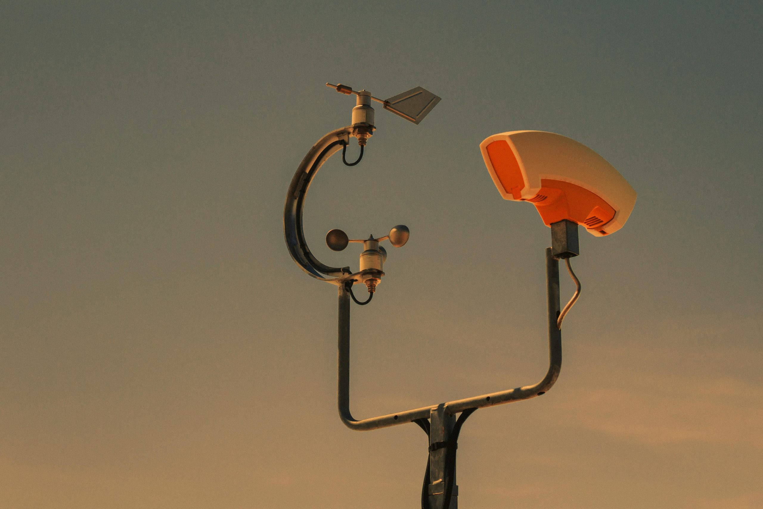 Weather monitoring equipment with a sunset sky backdrop, highlighting technology and atmosphere.