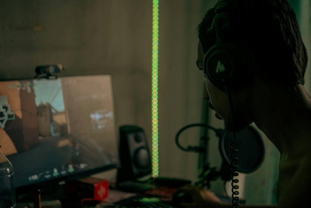 Focused gamer with headset playing a video game on a desktop computer indoors.