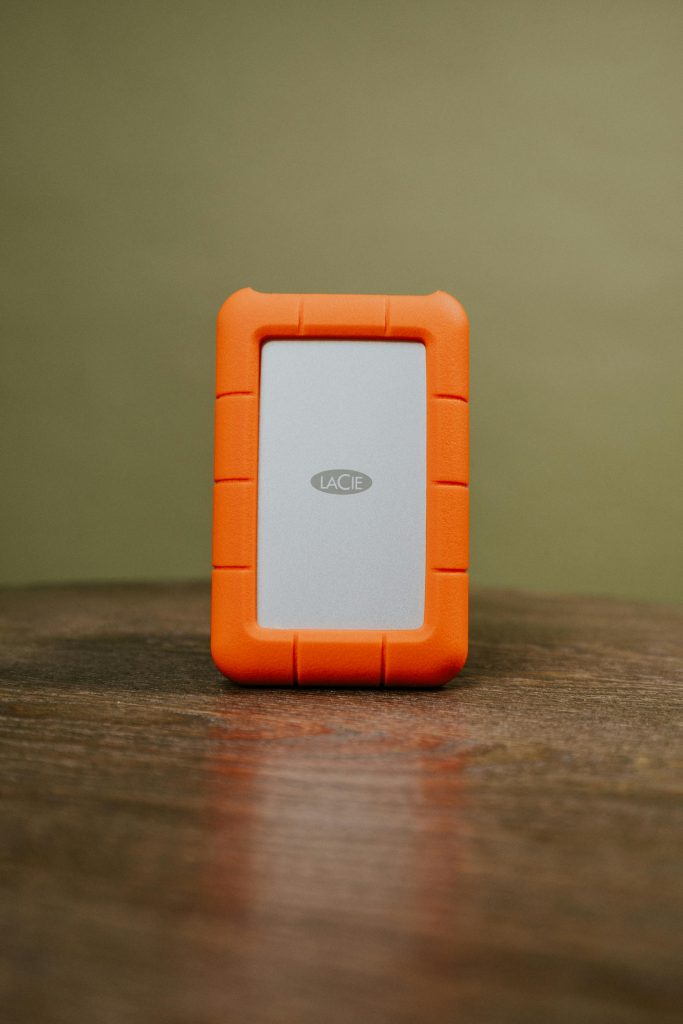 Orange-cased external hard drive on wooden surface, ideal for portable data storage solutions.