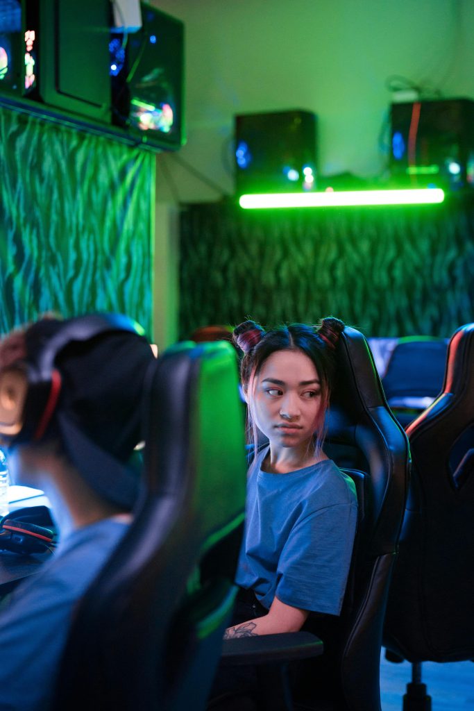 Young woman in a gaming room with neon lights playing on a gaming chair.