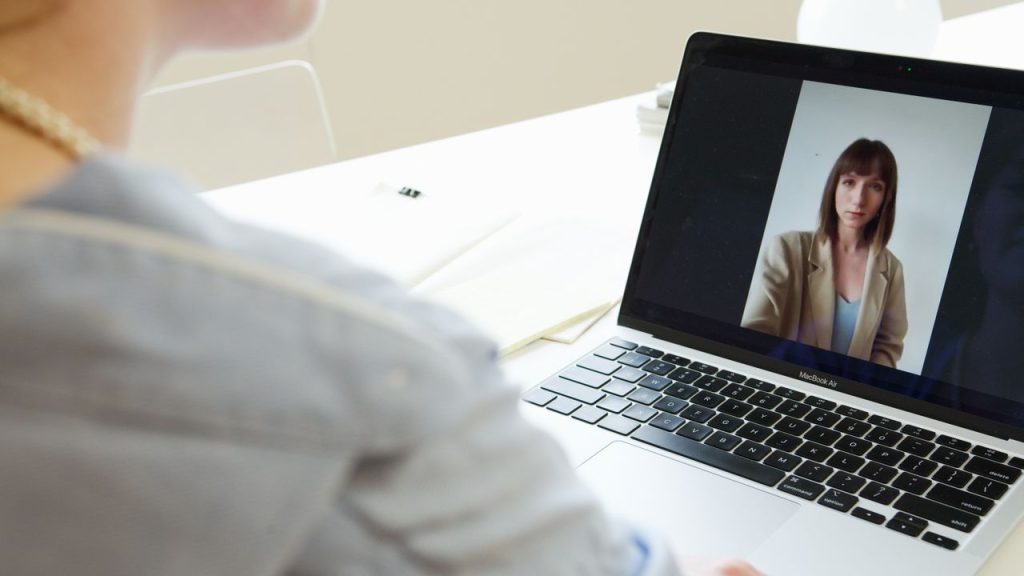 Close-up of woman on a video call using a laptop in a modern workspace.